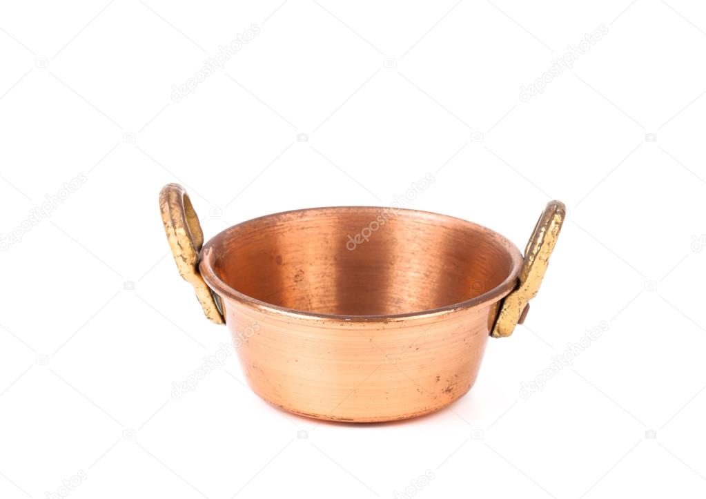 old copper pan with handles and with spots of rust on a white ba