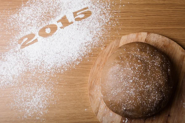 Inscription 2015 on flour and dough on a wooden table — Stock Photo, Image