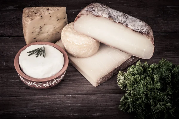Différents types de fromage sur fond de bois avec du persil. — Photo