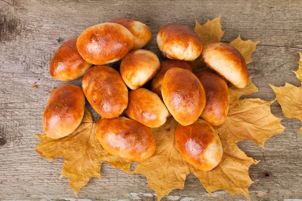 Empanadas de carne o repollo en las hojas de otoño en el fondo de madera —  Fotos de Stock