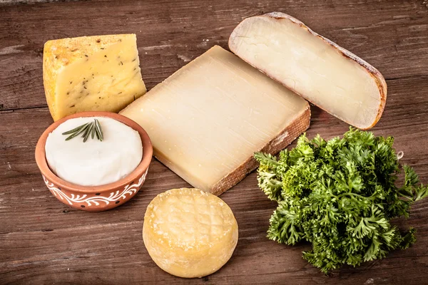 Différents types de fromage sur fond de bois avec du persil. — Photo