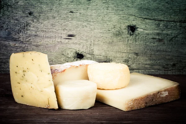 Various types of cheese on a wooden background. tinted — Stock Photo, Image