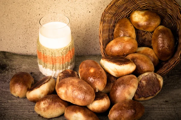 Tartes à la viande ou au chou dans un panier en osier et un verre de lait — Photo