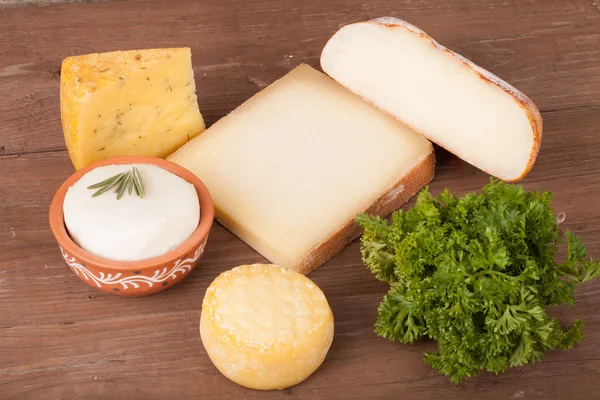 Différents types de fromage sur un fond en bois avec du persil — Photo