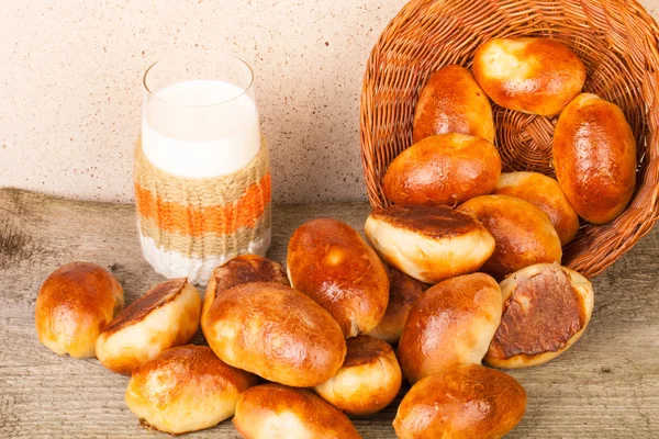 Pasteten mit Fleisch oder Kohl in einem Weidenkorb und einem Glas Milch — Stockfoto