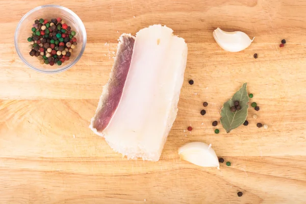 Raw bacon with spices on wooden table. — Stock Photo, Image