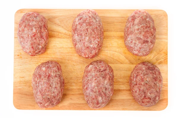 Empanadas de carne cruda en un tablero de madera sobre un fondo blanco — Foto de Stock