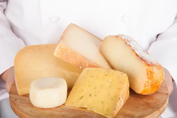 Olika sorter av ost på ett bräde i händerna från c — Stockfoto