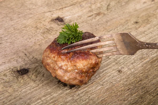 Cotoletta e fetta su una forchetta su un vecchio tavolo di legno — Foto Stock