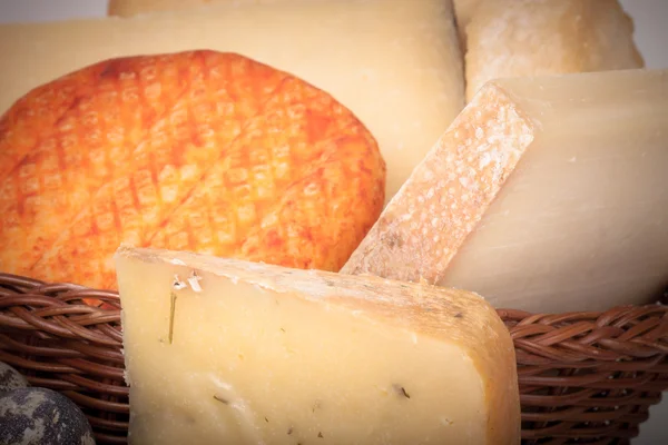 Several varieties of cheese in a wicker basket — Stock Photo, Image