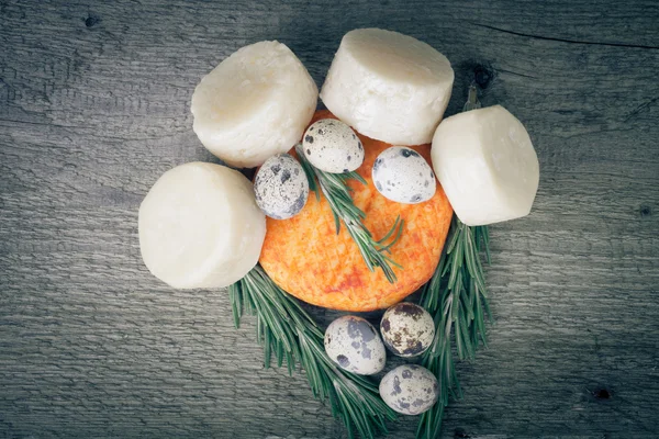 Teste di formaggio diverso, uova di quaglia e rosmarino su una t di legno — Foto Stock