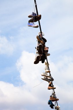 eski ayakkabılar mavi gökyüzü karşı elektrikli tel üzerinde asılı 