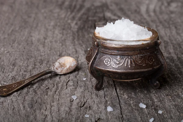海盐在旧的器皿和木制的桌子上的小勺子 — 图库照片