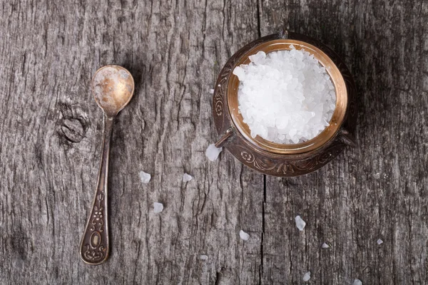 Sea salt in an old utensils and a small spoon on a wooden table — Stock Photo, Image