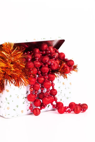 Tin box with red beads and tinsel on a white background — Stock Photo, Image