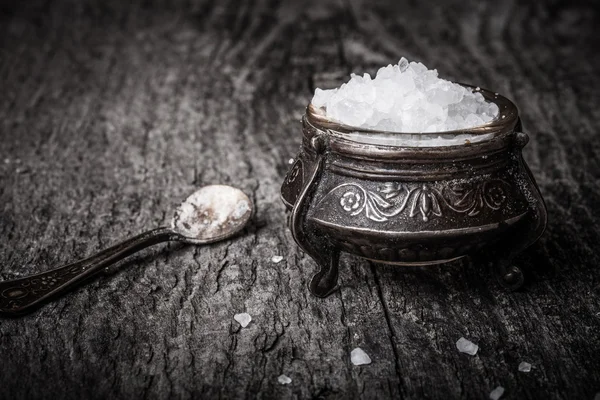 Sal do mar em uns utensílios velhos e uma colher pequena em uma mesa de madeira — Fotografia de Stock