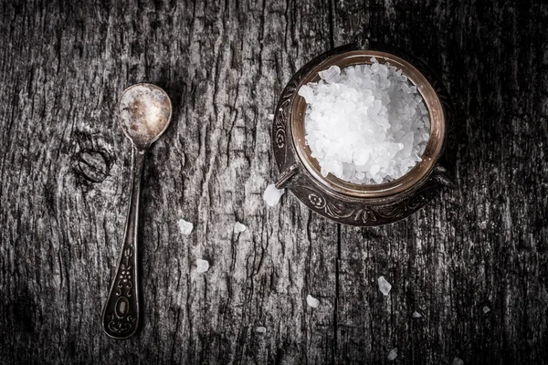 Sea salt in an old utensils and a small spoon on a wooden table — Stock Photo, Image