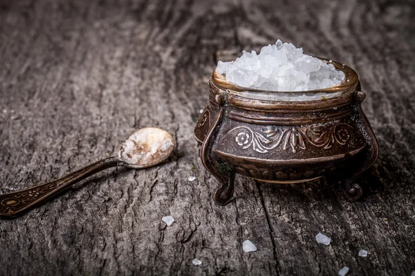 Sól morska w stare naczynia i małej łyżeczki na drewnianym stołem — Zdjęcie stockowe