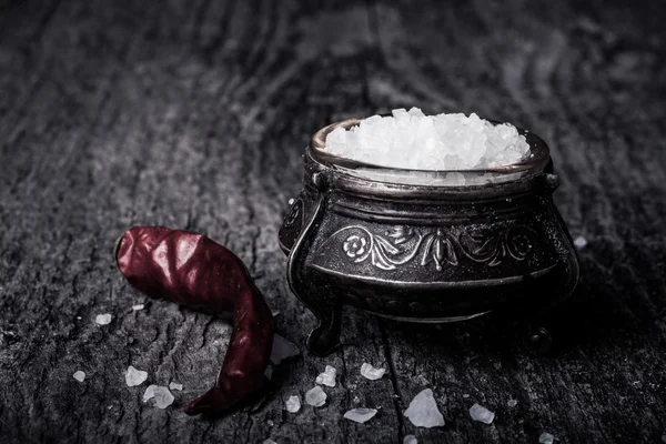 Sea salt in an old utensils and red hot chili peppers on a woode — Stock Photo, Image