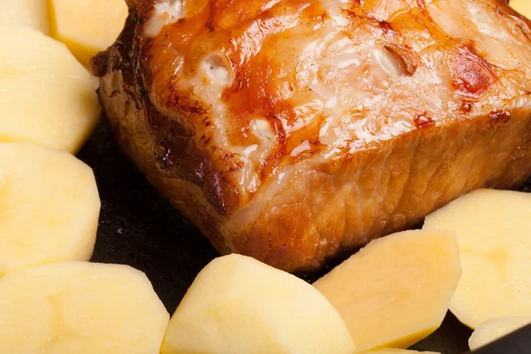 Pezzo di maiale, peperoni e patate in una vecchia tavola di legno — Foto Stock