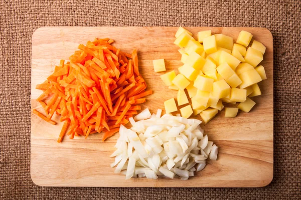Posiekaną cebulę, marchew, ziemniaki ułożonych w grupy na drewniane — Zdjęcie stockowe