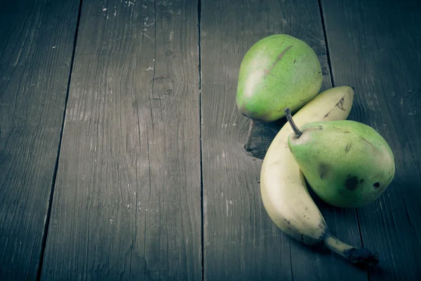 Pêras, bananas em uma velha mesa de madeira background.matizado — Fotografia de Stock