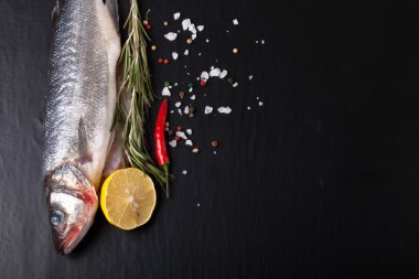 Taze deniz balığı koyu arka plan üzerinde baharatlarla yalan. T için alan