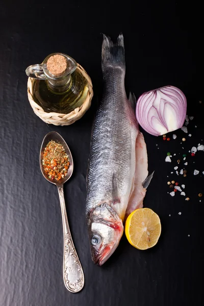 Fresh sea fish lying on dark background with spices. — Stock Photo, Image