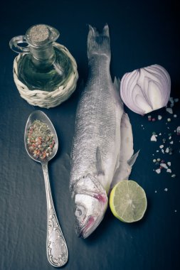 Taze deniz balığı koyu arka plan üzerinde baharatlarla yalan. renkli