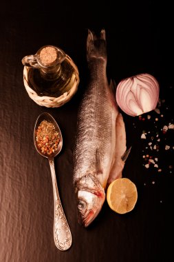 Taze deniz balığı koyu arka plan üzerinde baharatlarla yalan. Dikey