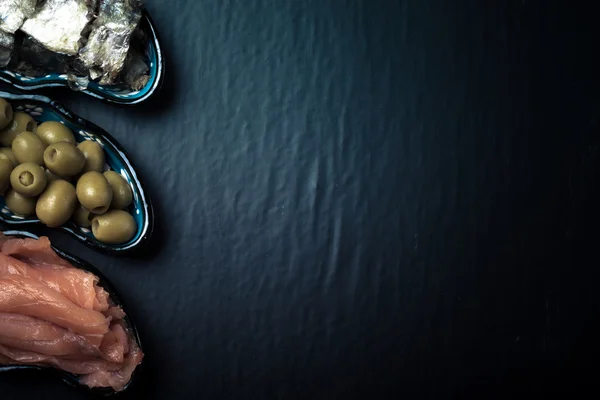 Fish assortment and olives on a plate on a dark background. With — Stock Photo, Image