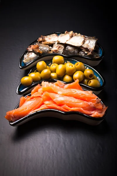 Assortimento di pesce e olive su un piatto su fondo scuro. Con — Foto Stock