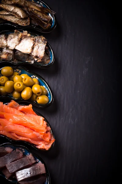 Fish assortment and olives on a plate on a dark background. With — Stock Photo, Image