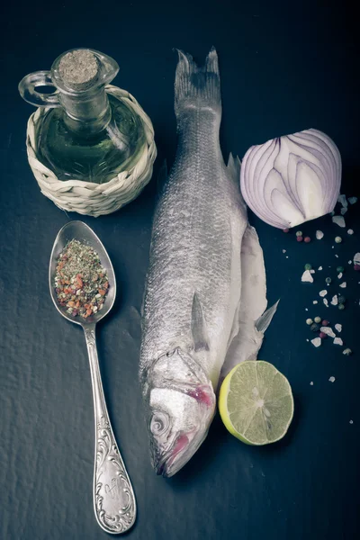 Taze deniz balığı koyu arka plan üzerinde baharatlarla yalan. renkli