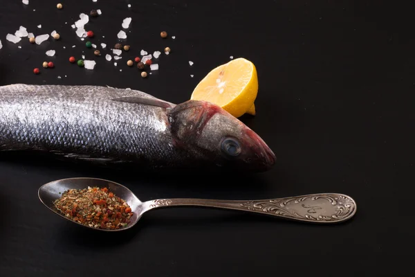 Fresh sea fish lying on dark background with spices. — Stock Photo, Image