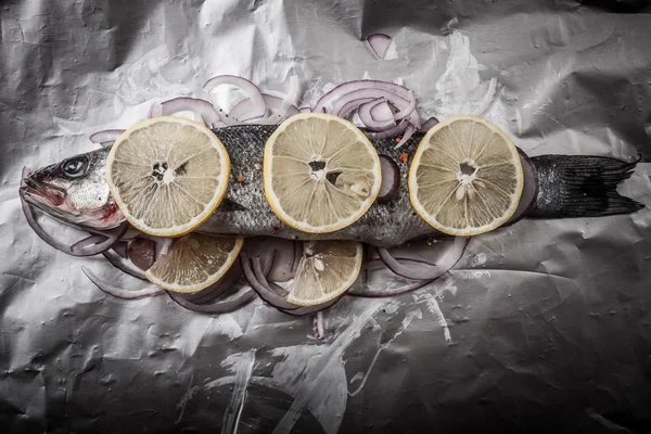 Pescado preparado para asar sobre papel de aluminio con limón y cebolla — Foto de Stock