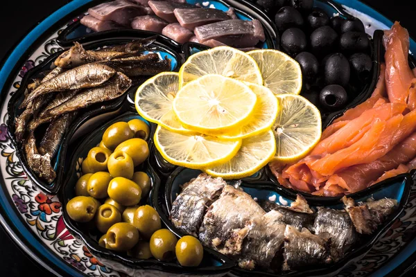 Pescado surtido en un plato sobre un fondo oscuro . — Foto de Stock