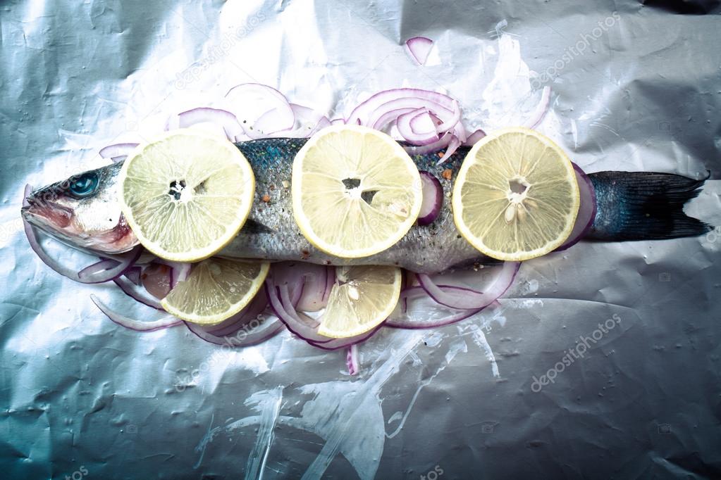 Fish prepared for roasting on the foil with lemon and onion