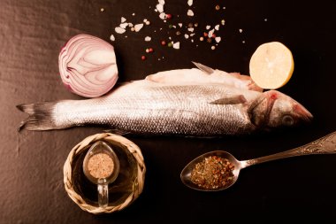 Taze deniz balığı koyu arka plan üzerinde baharatlarla yalan