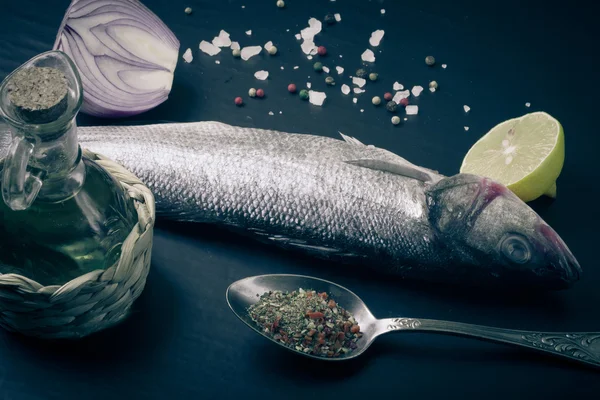 Fresh sea fish lying on dark background with spices. — Stock Photo, Image