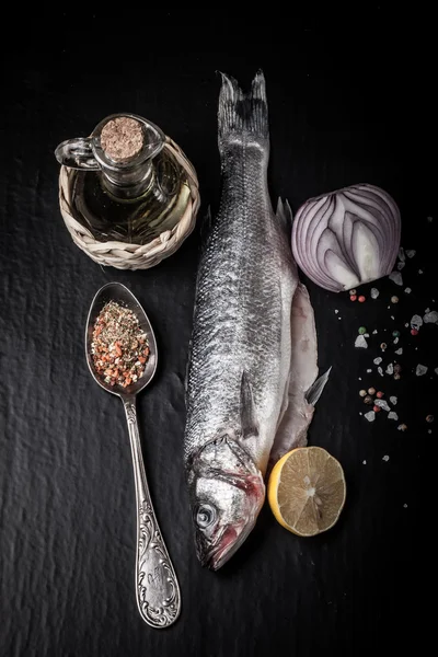 Fresh sea fish lying on dark background with spices. Vertical — Stock Photo, Image
