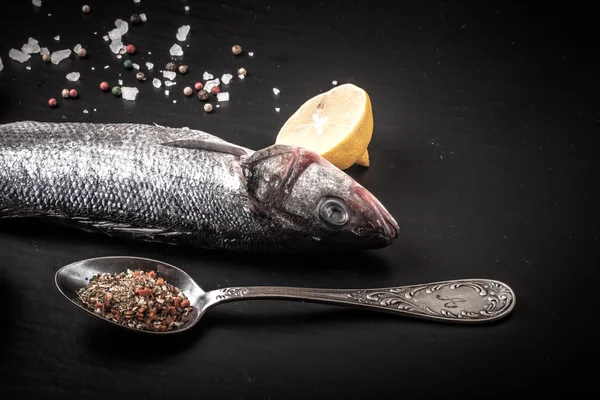 Taze deniz balığı koyu arka plan üzerinde baharatlarla yalan.