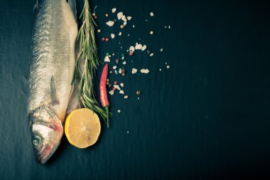 Taze deniz balığı koyu arka plan üzerinde baharatlarla yalan. T için alan