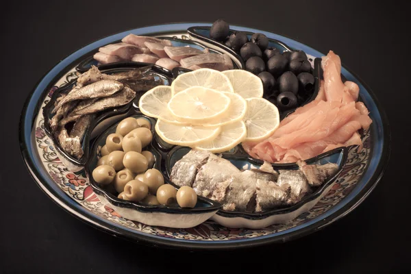 Peixe sortido em uma chapa em um contexto escuro . — Fotografia de Stock