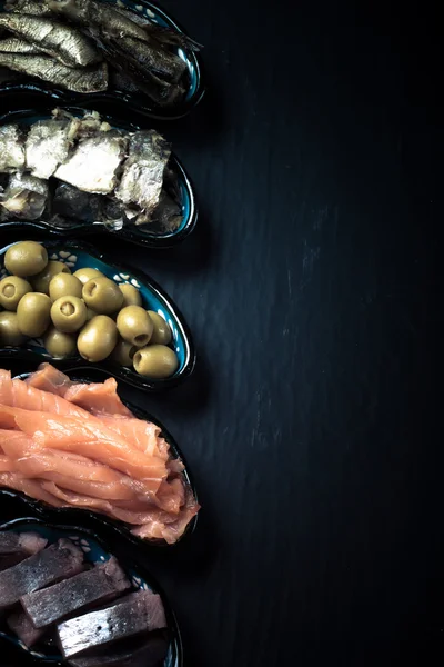 Fish assortment and olives on a plate on a dark background. With — Stock Photo, Image