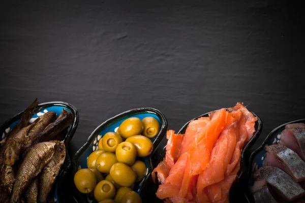 Balık çeşitliliği ve zeytin karanlık bir arka plan üzerinde bir tabakta. İle — Stok fotoğraf