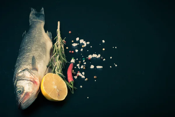 Pesce di mare fresco sdraiato su sfondo scuro con spezie. Spazio per t — Foto Stock