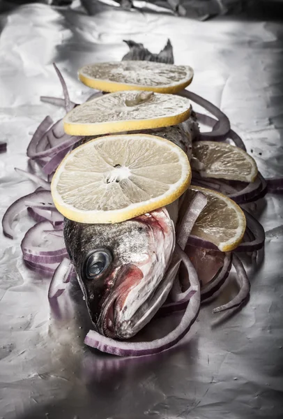 Fish prepared for roasting on the foil with lemon and onion.tint — Stock Photo, Image