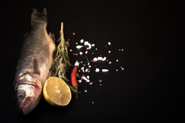 Taze deniz balığı koyu arka plan üzerinde baharatlarla yalan. T için alan