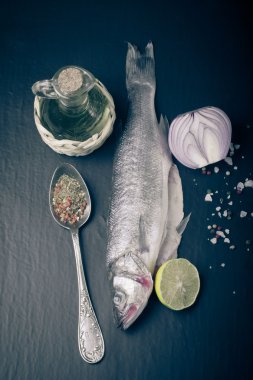 Taze deniz balığı koyu arka plan üzerinde baharatlarla yalan. Dikey. T